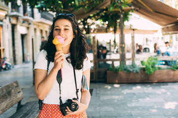 Happy young beautiful tourist woman enjoying a big ice cream