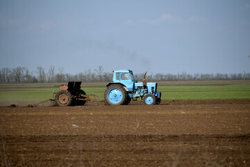 Obraz premium Rural business,tractor in field cultivates soil. Farming in spring