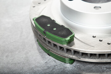 brake pads and perforated brake discs on a stone gray table