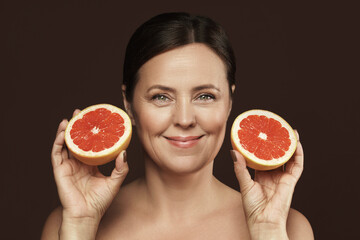 Beautiful and happy middle aged woman with a grapefruit in her hand