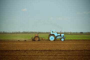 Blue tractor cultivating soil in spring,agriculture industry photo