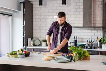 Copy space with man cutting vegetables in modern kitchen, preparing healthy food at home on a sunny day 