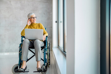 Senior business woman in wheelchair working in office