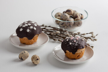 Easter cakes poured with chocolate with willow branches and Easter eggs on a white background