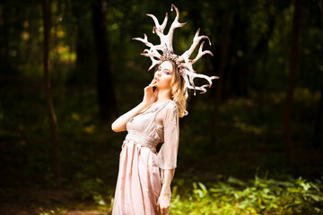 Beautiful Tranquil Caucasian Girl Posing With Artistic Deer Horns In Green Summer Forest With Brightly Lit Face.