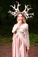 Beautiful Tranquil Caucasian Girl Posing With Artistic Deer Horns In Green Summer Forest With Brightly Lit Face.