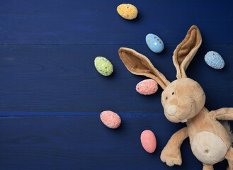 Fototapeta na wymiar decorative easter eggs and soft plush rabbit toy with long ears on a blue background