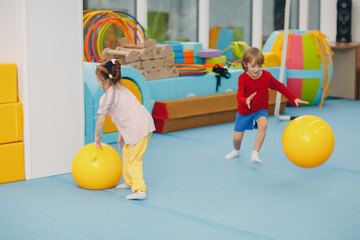 Kids doing exercises with big ball in gym at kindergarten or elementary school. Children sport and fitness concept.