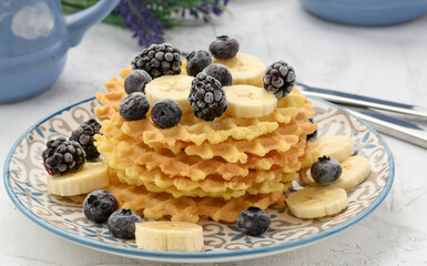 stack of baked Belgian waffles on a round plate with berries on a white table, delicious breakfast