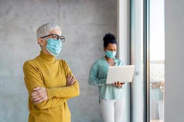 Happy business people wearing masks working in office