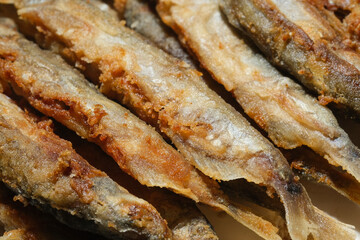 Pan fried fish on a plate. Small crispy fish. Capelin fried in oil with crispy breading. Selective focus