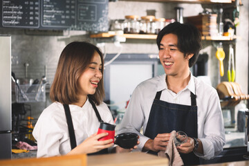 Two asian coffee waitress making cup of hot coffee latte in coffee shop cafe. Barista working with coffee machine in shop.