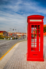 Porto Travel Destinations. Traditional Red Public Call Box in Porto City in Portugal At Daytime with Line of Houses on Background.