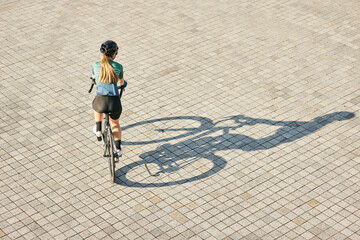 Aerial view shot of professional female cyclist riding bicycle, training outdoors on a warm sunny...