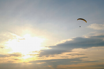 Paraglider flying into the sunset. Sky and sun landscape.