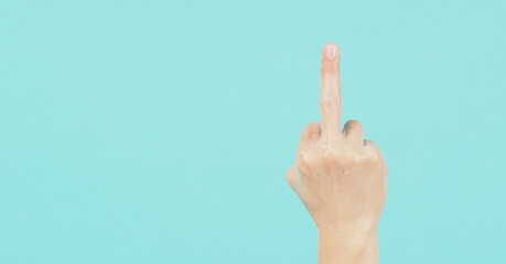 Hand is do fuck you hand sign and have foam soap bubbles on a green mint or Tiffany Blue background.isolated