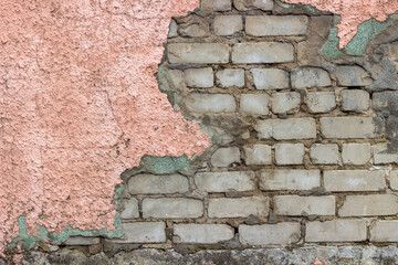brick wall behind pink plaster, wall of an old building