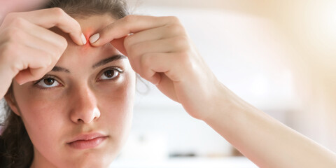 Naklejka premium teenage brunette pops zits looking at face reflection
