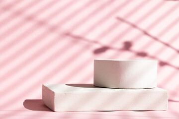Empty white podium on pastel pink background. Hard shadows. Minimal geometric podium. Scene with geometric shapes. Empty showcase for the presentation of cosmetic products.