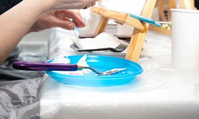palette knife for painting, stained in white paint on a blue stand, on the table