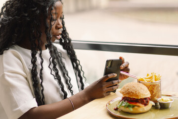 African woman using phone in cafe. People and technology