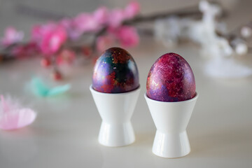 Easter concept. Two decorative eggs in white poached stands on  light background.