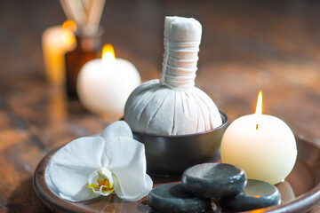 Fototapeta na wymiar Spa background. Towel, candles, flowers, aroma sticks, massaging stones and herbal balls. Massage, oriental therapy, wellbeing and meditation.