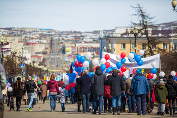 Obraz premium People with banners and balloons walk down the street during a May Day demonstration. Magadan, Magadan Region, Far East of Russia.
