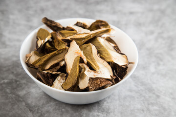 A plate with dried porcini mushrooms on a gray background. The concept of dehydration of products