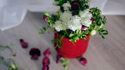 Flowers in a red box are on the floor, red roses with white flowers, a bouquet.