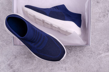 Knitted blue sneakers without laces on a gray background.