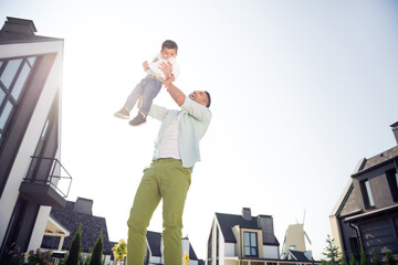 Full size photo of happy positive cheerful smiling family father hold son in air having fun enjoy free time outside outdoors