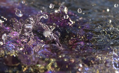 Wallpapers. Frozen movement of water. Drops of water falling and splashing. Sparkles, reflections of light. Vibrant purple color. 