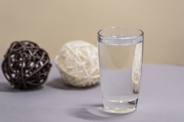 Transparent glass with water on background of decorative woven rattan balls