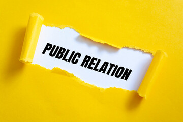 Torn yellow paper on white surface with Public Relation words.