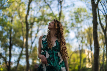 Fototapeta na wymiar Chica guapa joven dando un paseo y tomándose fotos en un parque verde en primavera