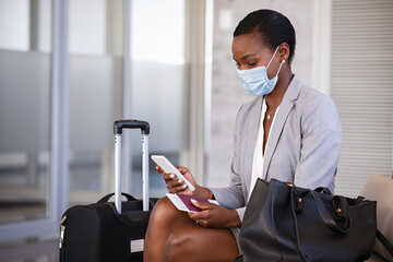 Business woman in airport with face mask checking phone