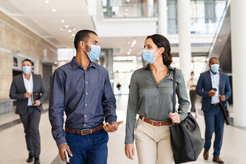 Businesspeople talking while walking with face mask
