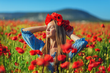 Close-up portrait of a happy beautiful young woman with a wreath of flowers on her head in a poppy field.