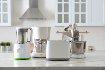 Modern toaster and other home appliances on white marble table in kitchen