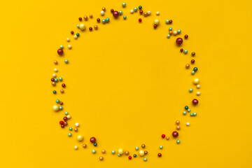Circle wreath shape made of colorful sprinkling on yellow background.  Easter celebration concept. Top view.