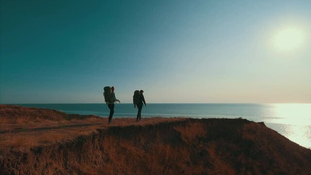 The couple walking on the mountain on a sunset background