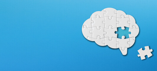 Brain shaped white jigsaw puzzle with copy space on blue background, a missing piece of the brain puzzle, mental health and problems with memory - obrazy, fototapety, plakaty