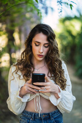 Chica joven guapa en un parque usando el smartphone y dando un paseo en primavera