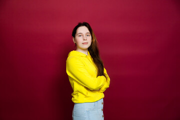 Portrait of   russian teen girl in  yellow hoodie  on  red    background