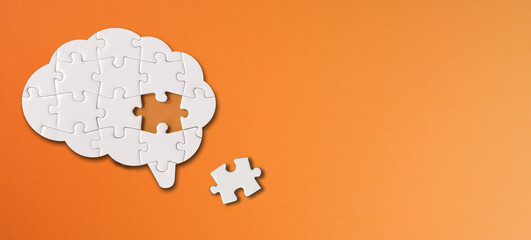 Brain shaped white jigsaw puzzle with copy space on orange background, a missing piece of the brain puzzle, mental health and problems with memory - obrazy, fototapety, plakaty