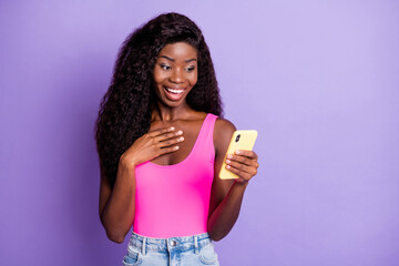 Photo of adorable excited dark skin woman dressed pink tank top chatting device arm empty space isolated violet color background