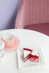 Red velvet cake on a white table with a pink tea mug