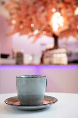 A cup of coffee against the blurry background of a restaurant bokeh.