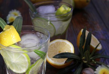 Glass with iced lemonade decorated with green leaves and lemon slices. 